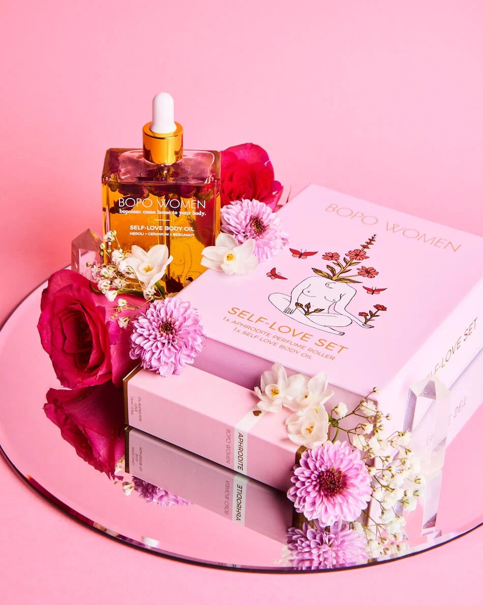 Bath and body products with flowers on a pink background