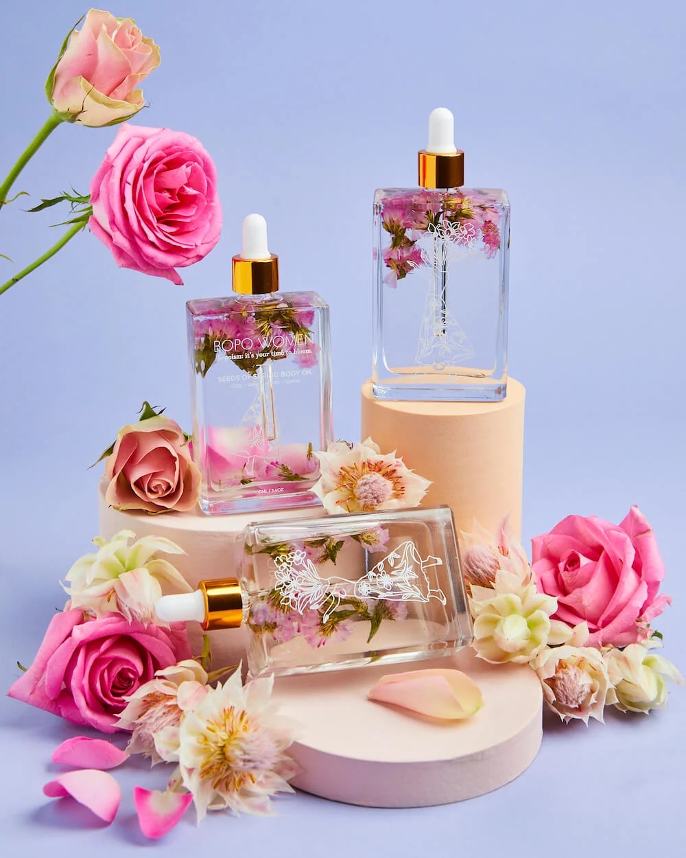 Cosmetic bottles with floral elements on a light purple background
