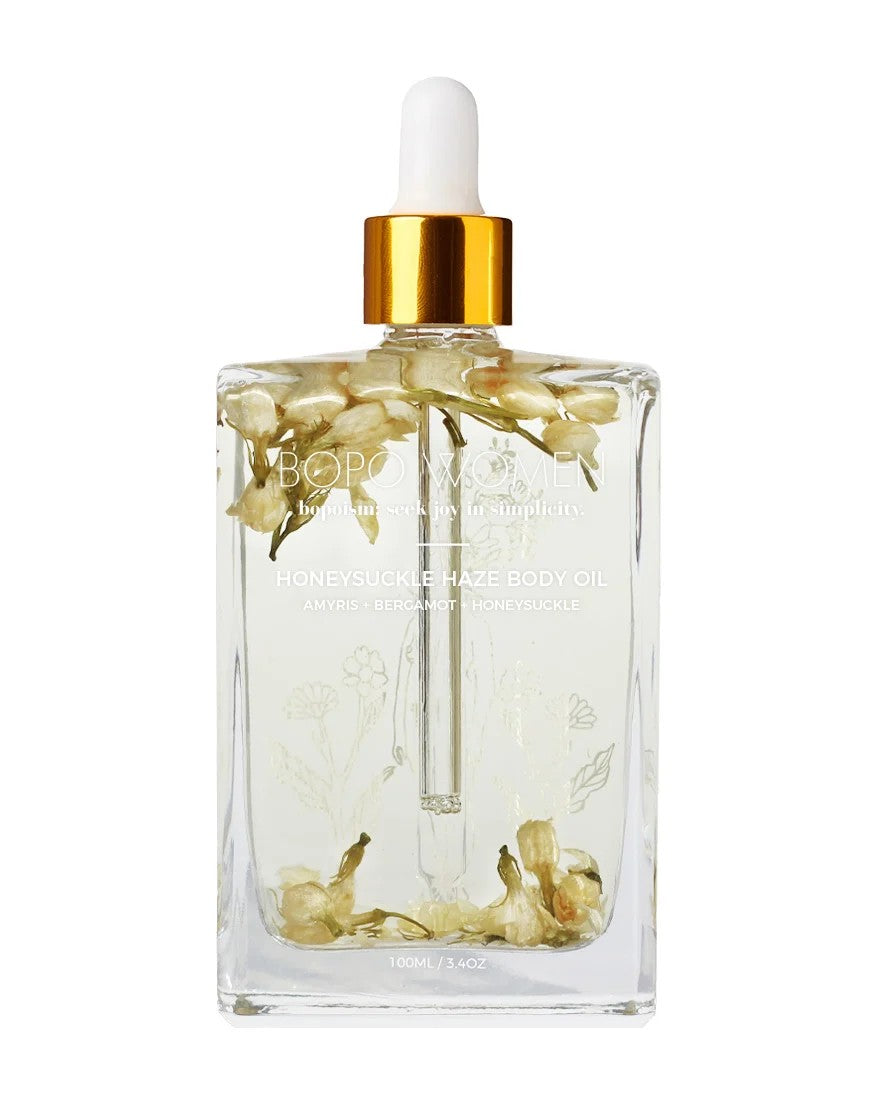Clear glass bottle with gold cap, white box labeled 'Boro Women', and yellow flowers on a beige background