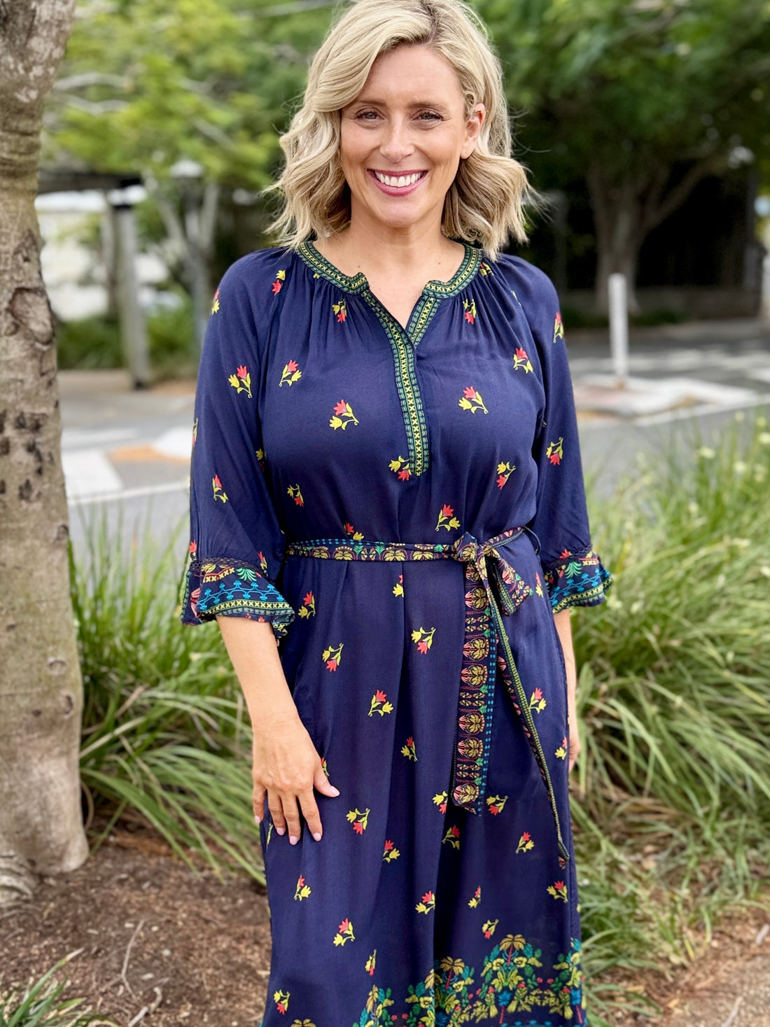 navy blue midi dress with colorful floral prints and green trim 