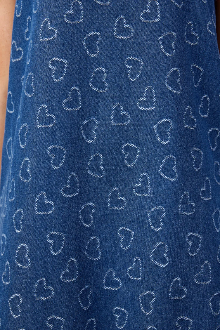 A close-up of a blue fabric with a repeating pattern of white outlined hearts.