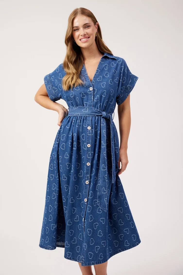 A woman modeling a blue midi dress with a white heart pattern, short flutter sleeves, a V-neckline, and a matching waist tie, 