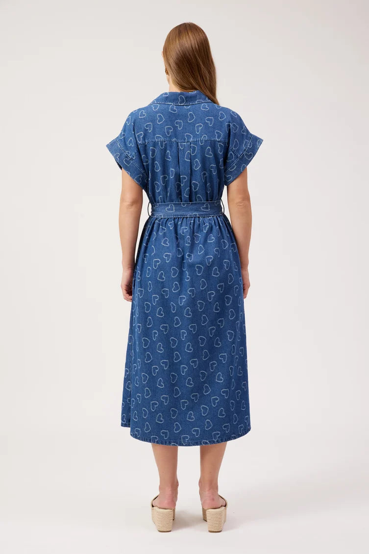 A woman viewed from the back wearing a blue midi dress with a white paisley pattern, short sleeves, and a tie waist