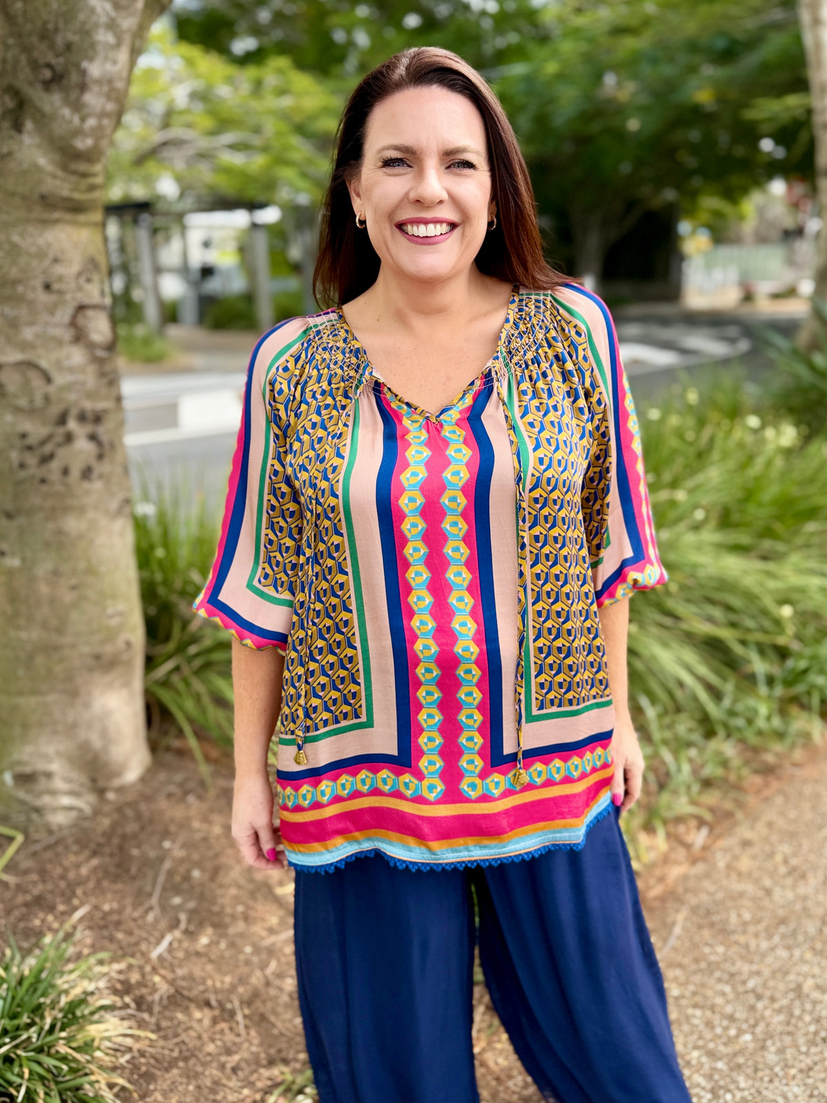 colorful short-sleeve patterned top with blue pants.