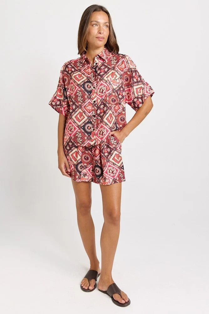 Matching set with short-sleeve collared shirt and  short with a colourful geometric and medallion pattern in red, pink, black, and white, 