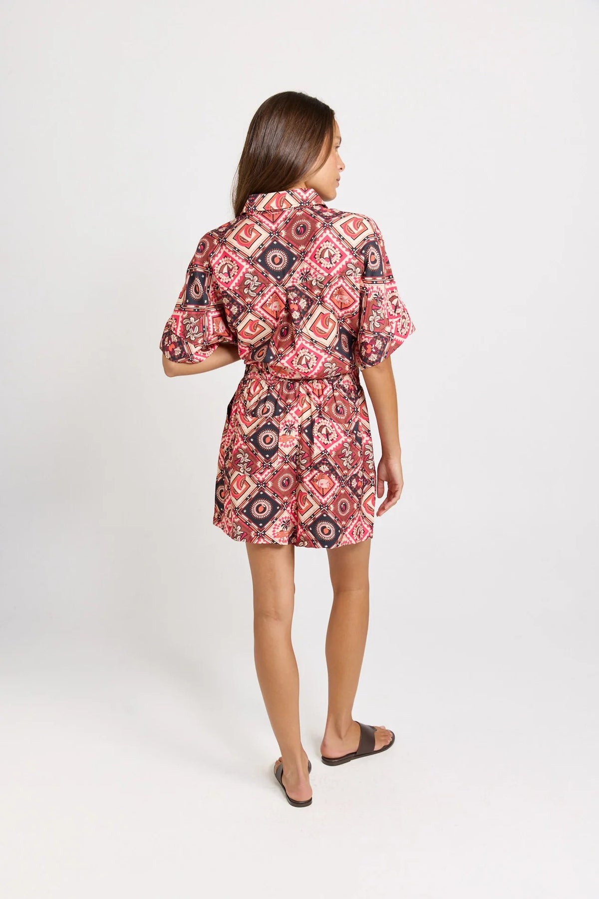 Matching set with short-sleeve collared shirt and  short with a colourful geometric and medallion pattern in red, pink, black, and white, 