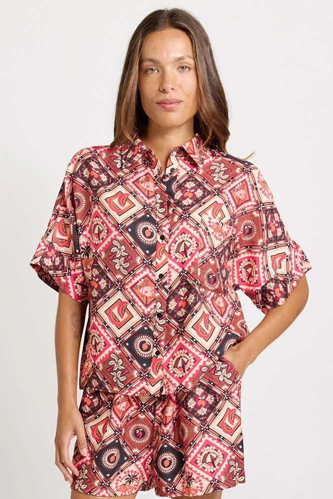 Matching set with short-sleeve collared shirt and  short with a colourful geometric and medallion pattern in red, pink, black, and white, 