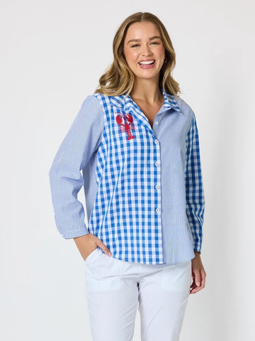 Women’s blue and white mixed‑pattern shirt featuring vertical stripes and gingham checks with red embroidered lobsters, styled with white pants — coastal casual outfit.
