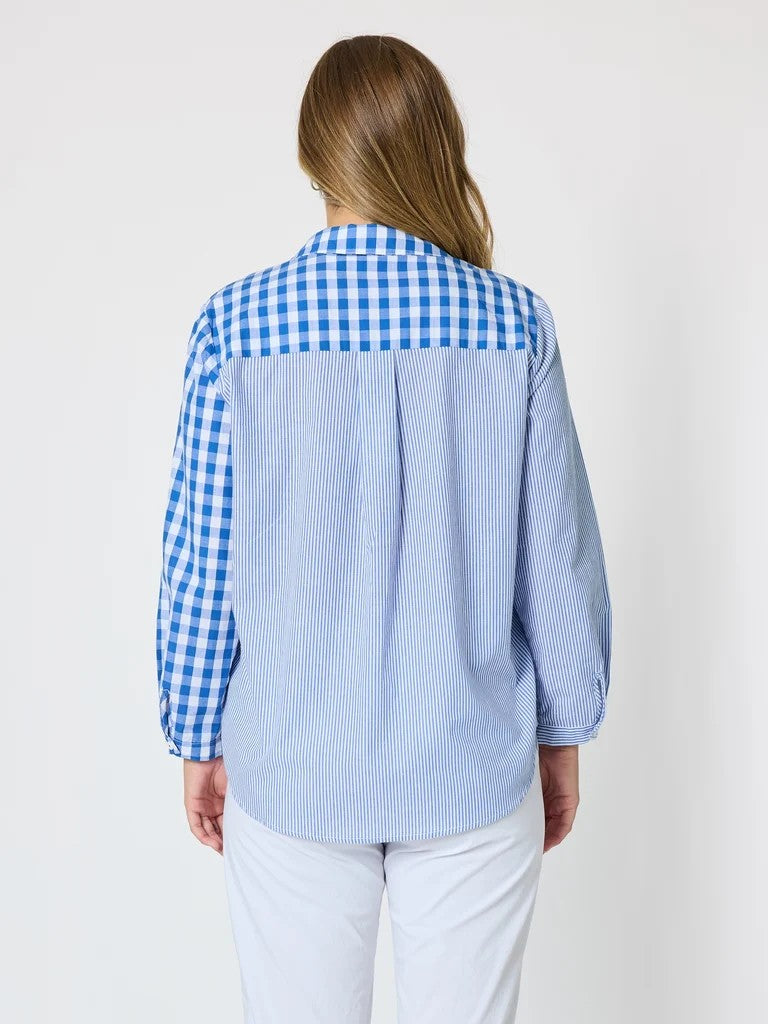 Women’s blue and white mixed‑pattern shirt featuring vertical stripes and gingham checks with red embroidered lobsters, styled with white pants — coastal casual outfit.